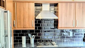 Een keuken met houten kastjes, een gasfornuis en een roestvrijstalen oven.