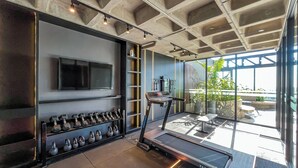 Un gimnasio moderno con una cinta de correr, pesas y un televisor en la pared.