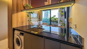 Una cocina moderna con lavadora integrada, un espejo grande y plantas en macetas.