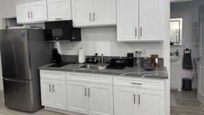 Una cocina moderna con armarios blancos, un refrigerador de acero inoxidable, un microondas y un fregadero.