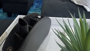 Una sala de estar moderna con un sofá negro, un tapete azul y una mesa de centro blanca texturizada.