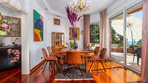 Uma sala de jantar com uma mesa de madeira, cadeiras de couro, um candelabro e obras de arte nas paredes.