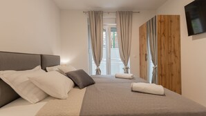 A bedroom with a bed, pillows, a TV, and a wooden wardrobe.