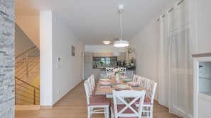 Een moderne keuken met een eethoek, houten vloer en een trap.
