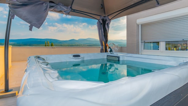 A hot tub on a rooftop terrace with a view of mountains.