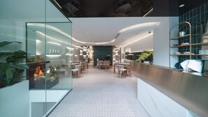 A modern interior with a glass partition, seating area, and a counter with shelves. - IconSphere Hotel (Ho Chi Minh City)