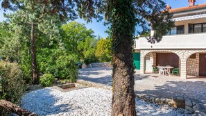 A courtyard with a stone pathway, a small garden area with white pebbles, and a building with a stone facade and green shutters. - Villa Laura with heated pool - Krk by Villas Guide (Krk)