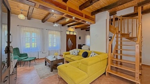 Un soggiorno con un divano giallo, una scala in legno e una poltrona verde.