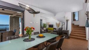 Un espacio de estar moderno con comedor, asientos, televisión y chimenea.