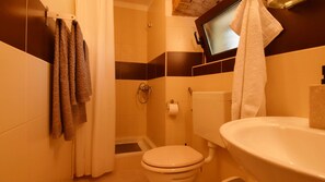 Un baño pequeño con inodoro, lavabo y ducha.