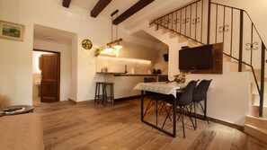 Amplia sala de estar con piso de madera, una mesa de comedor con sillas, una cocina de diseño moderno y una escalera con barandilla decorativa.