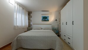 A bedroom with a bed, a wardrobe, a painting, and a window with curtains.