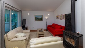 Una sala de estar con un sofá beige, un sofá rojo, una mesita, una chimenea y un cuadro en la pared.