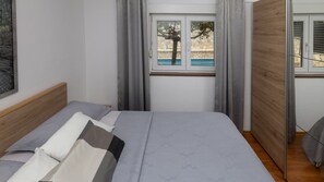 Un dormitorio con cama, ventana con cortinas y vistas a un espacio exterior.