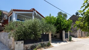 A residential property with a stone wall, a metal gate, and a tree in front.