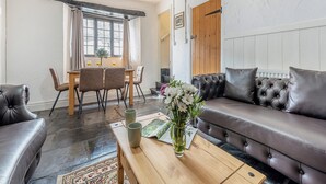 A living room with a sofa, a coffee table, a dining table with chairs, and a fireplace. - 2 bedroom accommodation in Umberleigh (Umberleigh)