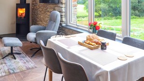Comedor con pared de piedra, chimenea y ventana grande con vistas a zonas verdes.