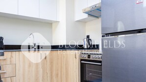 Eine moderne Küche mit Holzschränken, einem Edelstahlkühlschrank und einem eingebauten Backofen.