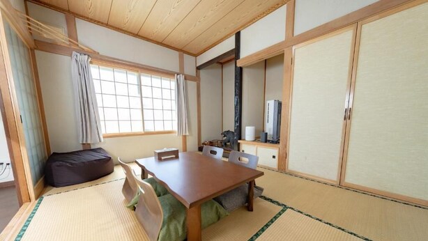 Una tradizionale stanza giapponese con pavimento in tatami, un tavolino in legno e porte scorrevoli.