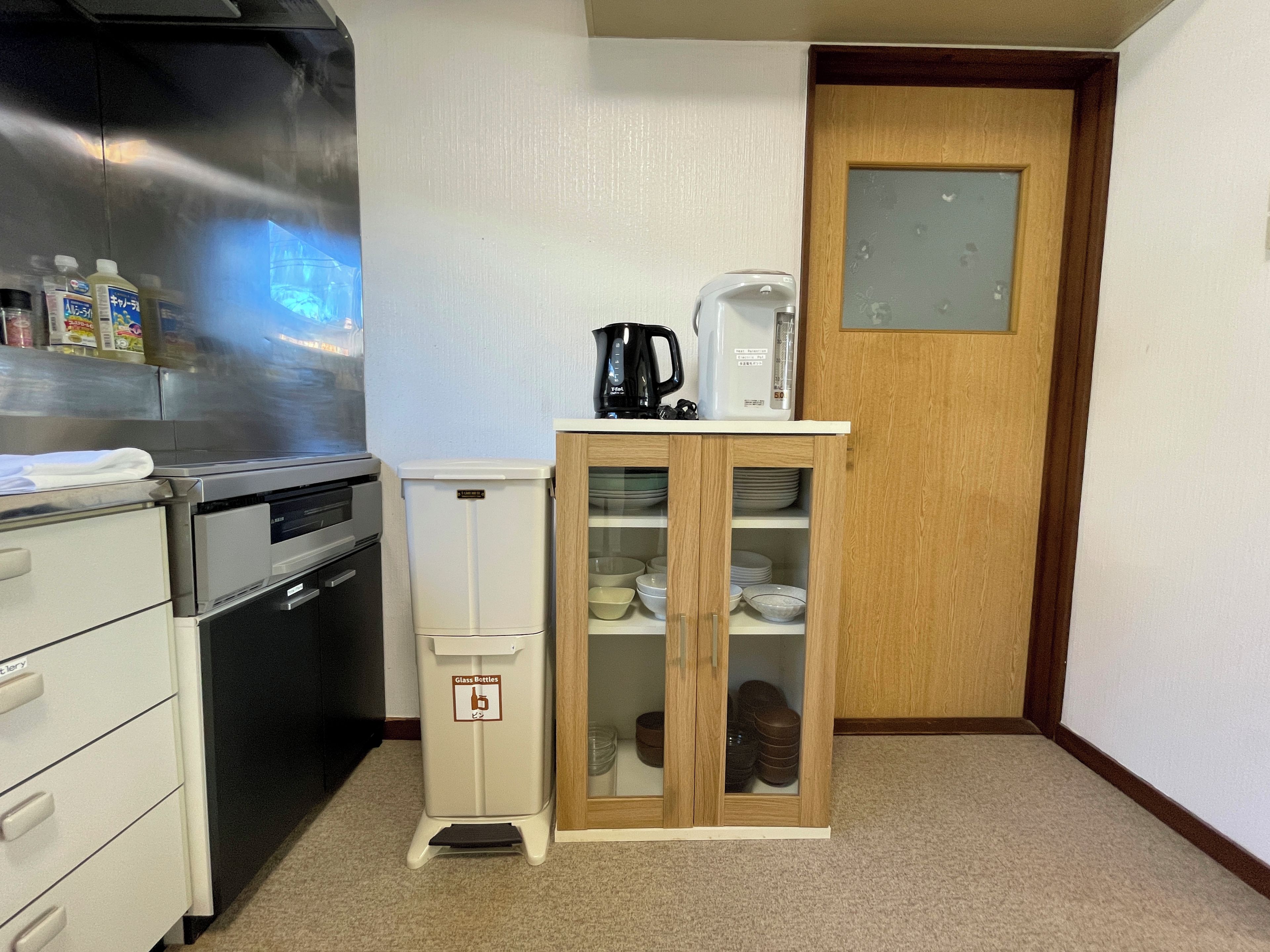 Eine kleine Küche mit einem Kühlschrank, einer Kaffeemaschine und einem Schrank mit Gläsern.