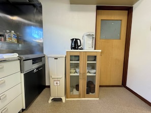 A compact kitchen with a refrigerator, a coffee maker, and a cabinet with glassware. - FURANO RETREAT (Furano)