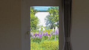 Una stanza con una finestra, una tenda e vista su un giardino fiorito.