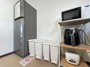 A kitchenette with a refrigerator, microwave, coffee maker, and waste bins. - FURANO RETREAT (Furano)