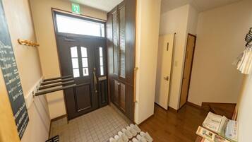 A hallway with a door, a shoe rack, and a small table with books.
