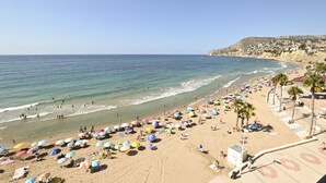 Une plage parsemée de nombreux parasols colorés, où les gens profitent de la mer.