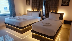 Une chambre d’hôtel avec deux lits, chacun doté d’un piédestal en marbre et de linge de lit blanc.
