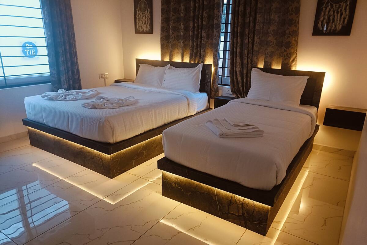 Quarto de hotel com duas camas, cada uma com base de mármore e roupa de cama branca.