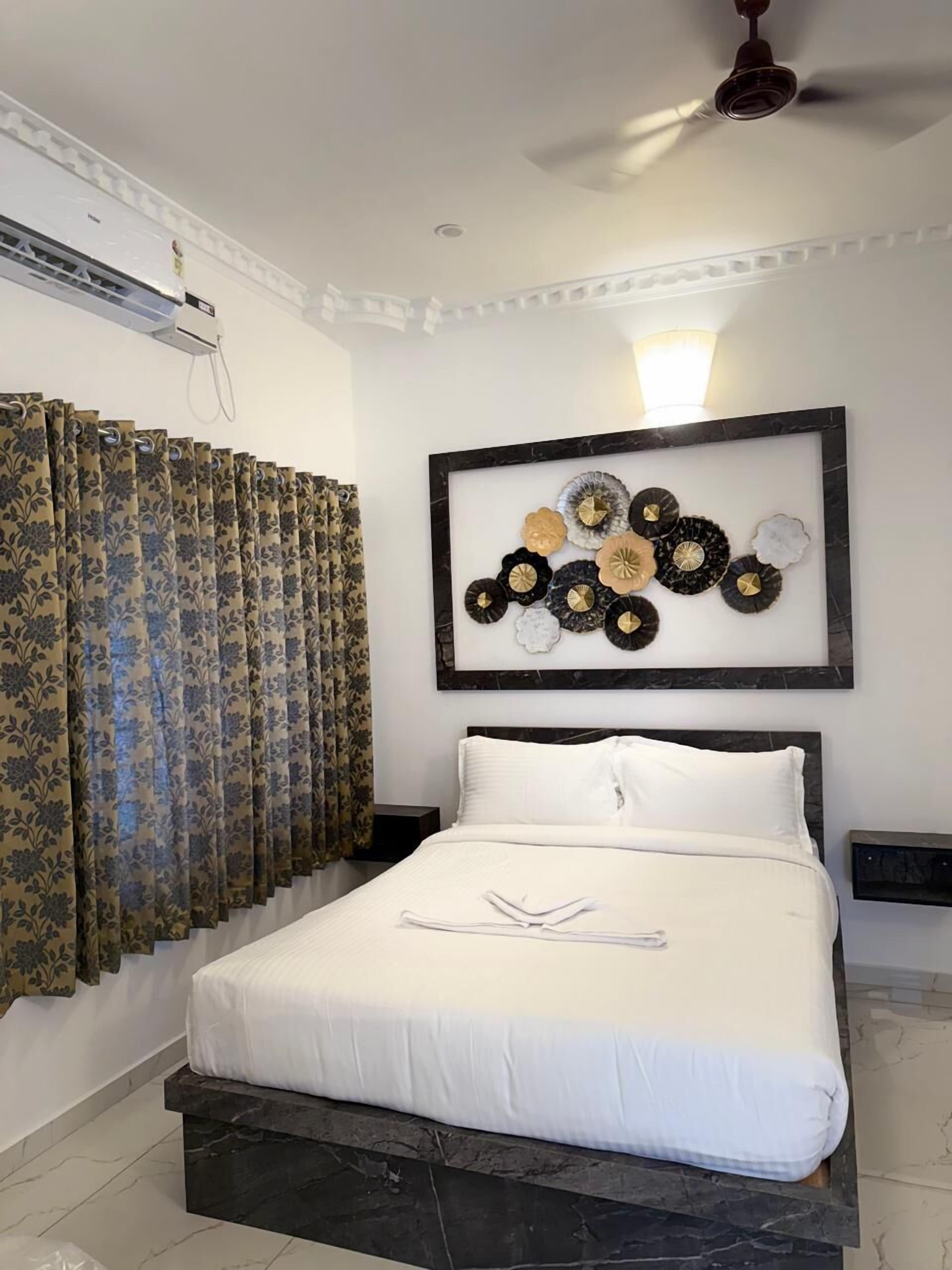 A bedroom with a bed, curtains, a ceiling fan, and a wall-mounted artwork.