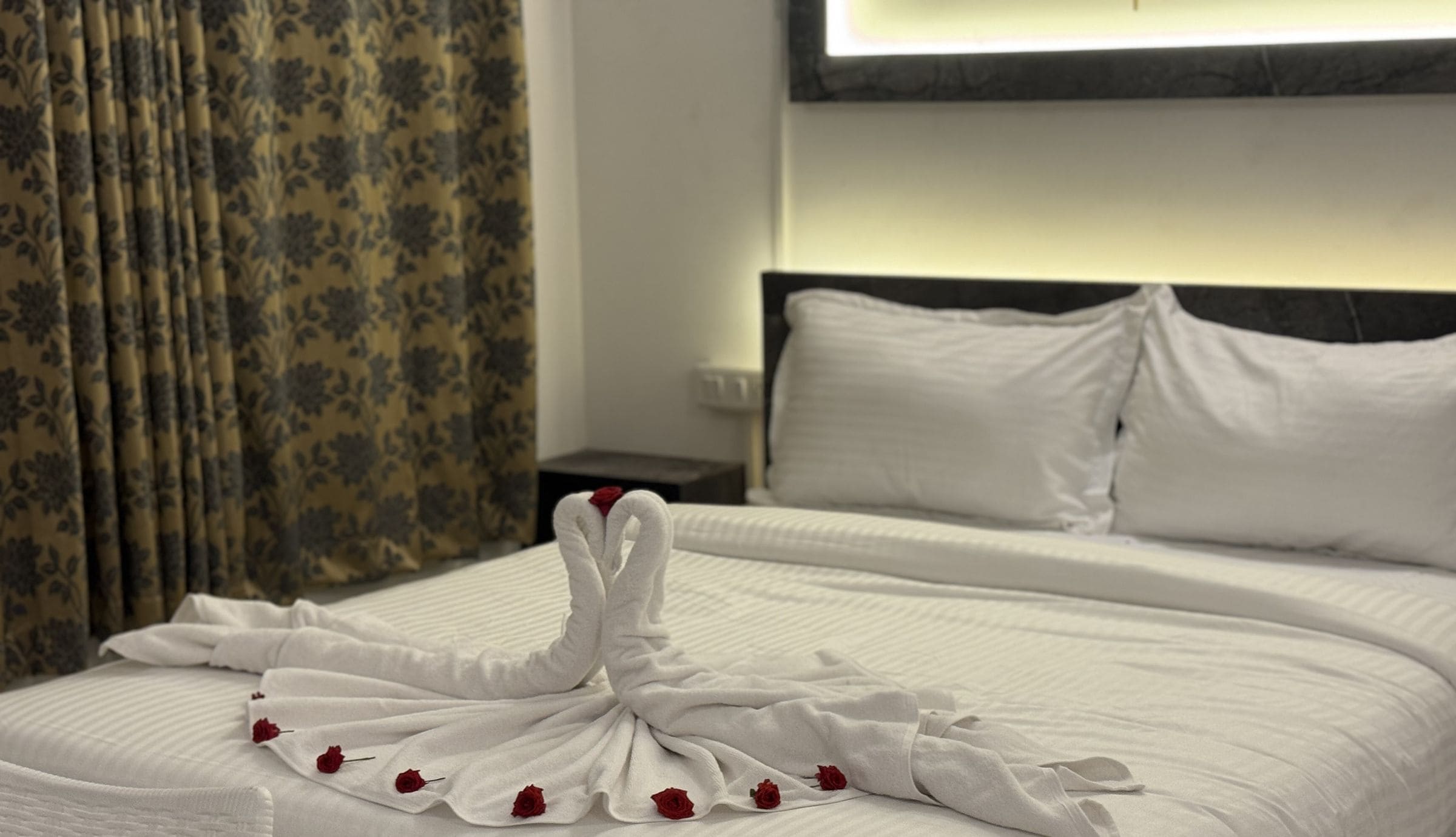 Ein Hotelzimmer mit einem ordentlich bezogenen Bett, einem Kopfteil und einem Nachttisch.