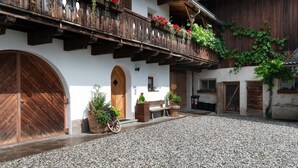Un bâtiment doté d’un balcon en bois, d’une grande porte en bois et d’une cour recouverte de gravier.