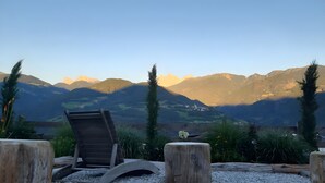 A wooden deck chair overlooking a mountainous landscape with a clear sky.
