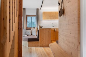 Una stanza compatta con un letto, un angolo cottura piccolo e una parete in legno.
