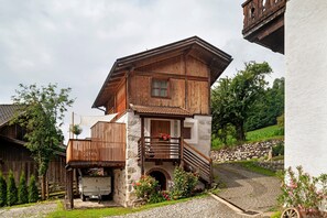 Een houten huis met twee verdiepingen, een stenen fundering, een balkon en een kleine garage.