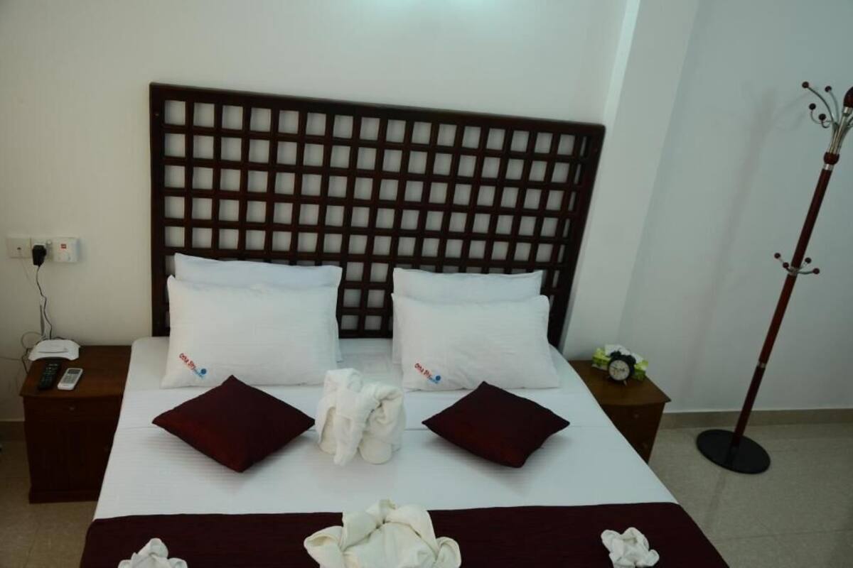 Ein Hotelzimmer mit einem großen Bett, zwei Nachttischen, einem Telefon und einem Kleiderständer.