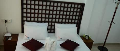 A hotel room with a large bed, two bedside tables, a telephone, and a coat stand.