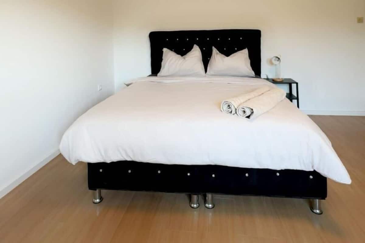 Un dormitorio con cama, mesita de noche y lámpara de pared.