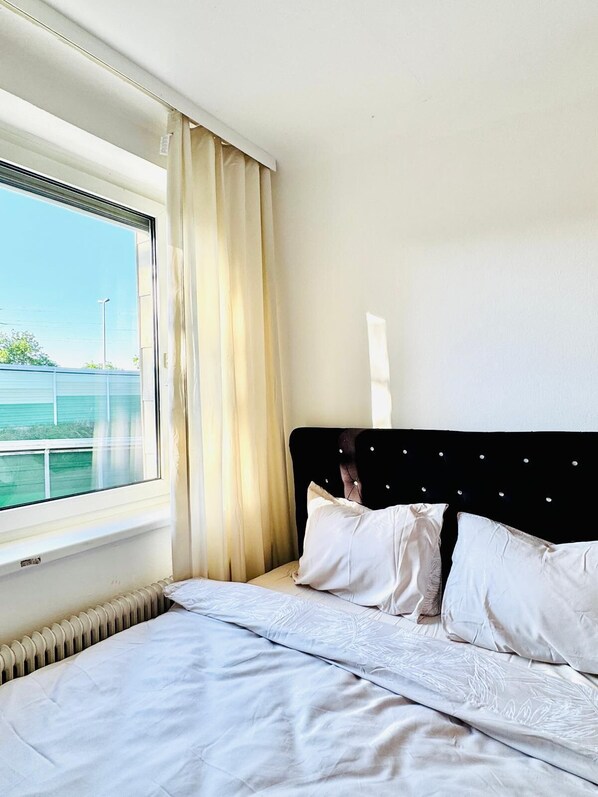Habitación de hotel con cama, ventana con cortinas y vista al mar.