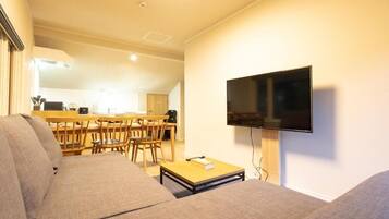 A living room with a sofa, a coffee table, and a TV mounted on the wall.