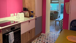 A kitchen with pink walls, a wooden cabinet, a glass countertop, and a patterned floor.