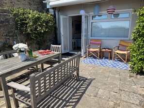 A patio with a table, chairs, and a small garden area. - Quay Rocks, wonderful three bedroom ground floor holiday home with sea views (Seaview)