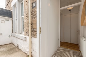A narrow hallway with a white door, a small window, and a patterned floor. - Melbourne Place (No 23) (St Andrews)