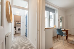A modern kitchen with a dining area, a washing machine, and a blue door. - Melbourne Place (No 23) (St Andrews)