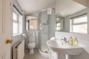 A bathroom with a glass-enclosed shower, a white sink, and a toilet. - Melbourne Place (No 23) (St Andrews)