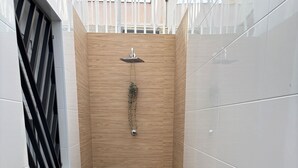 Un bagno moderno con doccia, una panca e un tavolino con una tazza.