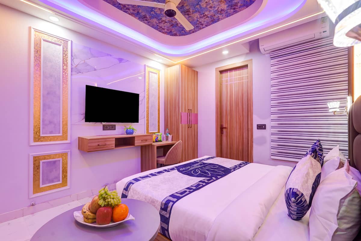 A modern bedroom with a flat-screen TV, wooden wardrobe, and a bed with a patterned bedspread.