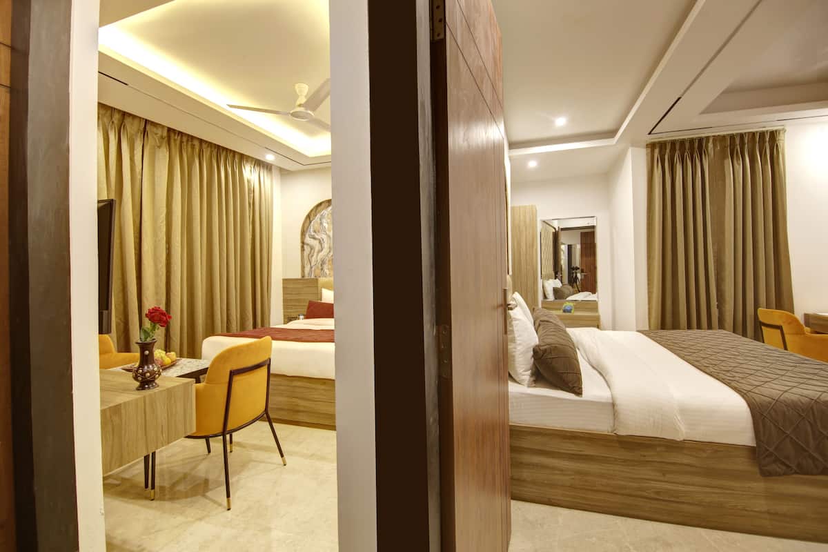 A hotel room with a bed, bedside table, chair, and a desk with a chair.